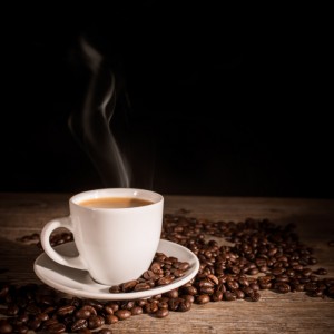 Cup of coffee and coffee beans on wooden background